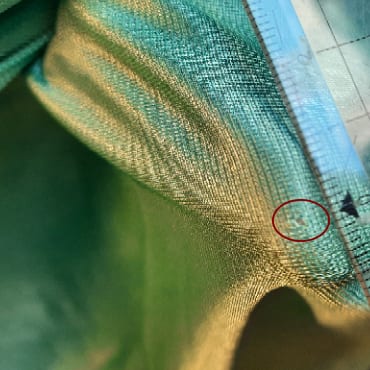 Weißes Tuch mit zentralem, ausgefranstem Loch. Ein weißes Tuch mit einem zentralen, unregelmäßigen Loch. Das feine Material ist an den Kanten des Lochs ausgefranst.