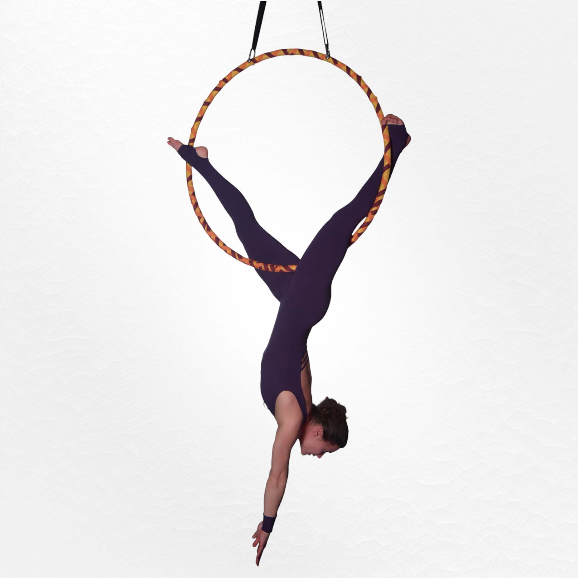Artistin bei einer Luftakrobatik-Performance am Aerial Hoop Eine Artistin während einer Luftakrobatik-Vorführung führt eine elegante Pose an einem Luftring aus, der an der Decke befestigt ist. Sie trägt einen figurbetonten Anzug, der ihre Bewegungen betont. Der schlichte Hintergrund lenkt den Fokus auf ihre akroba